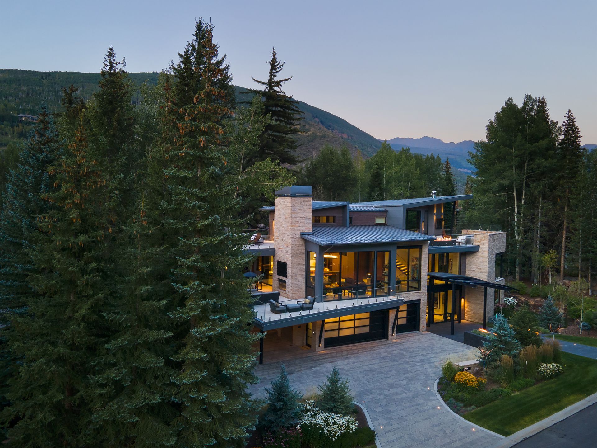 An aerial view of a large house surrounded by trees and mountains.