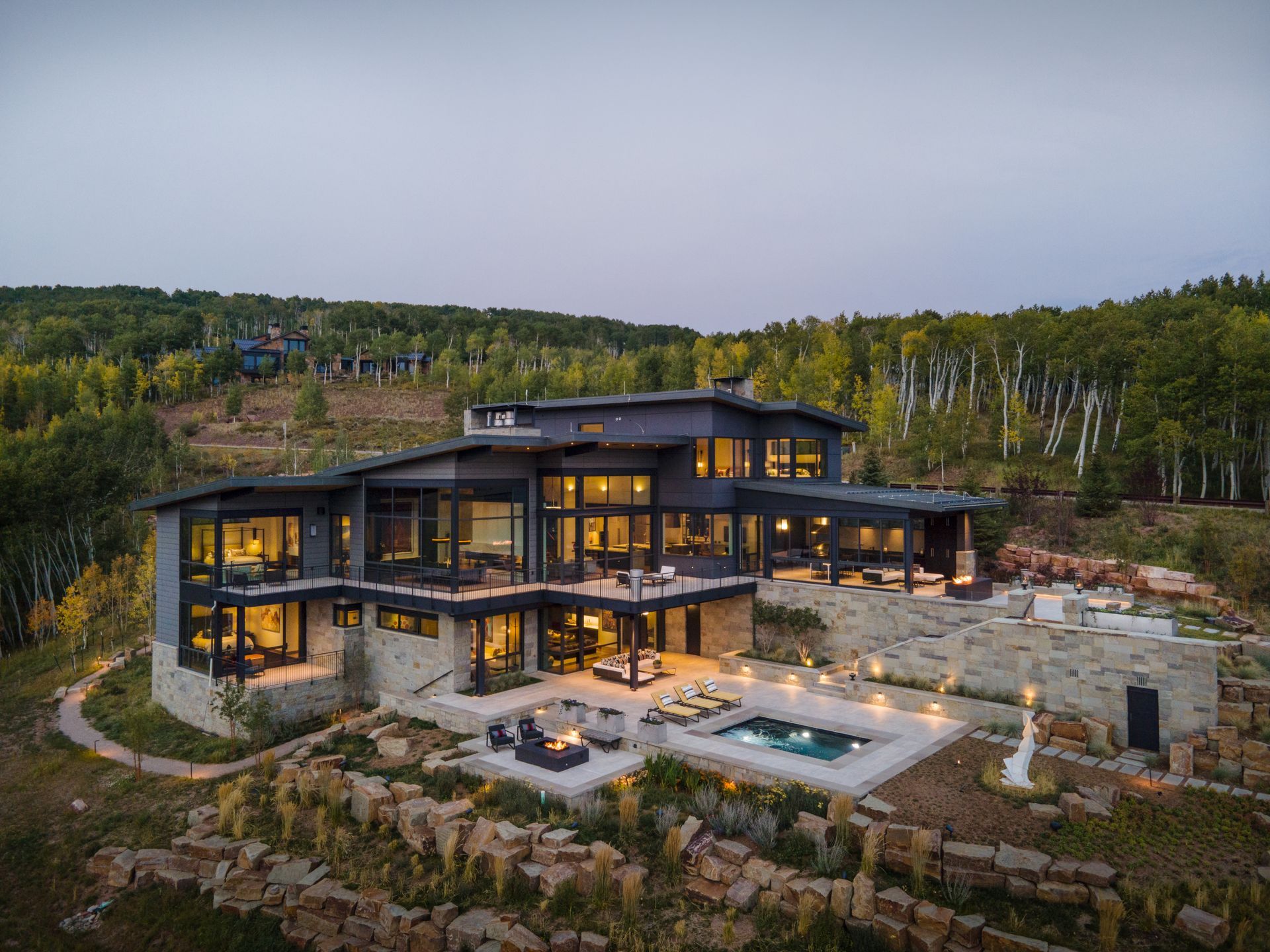 An aerial view of a large house with a swimming pool surrounded by trees.