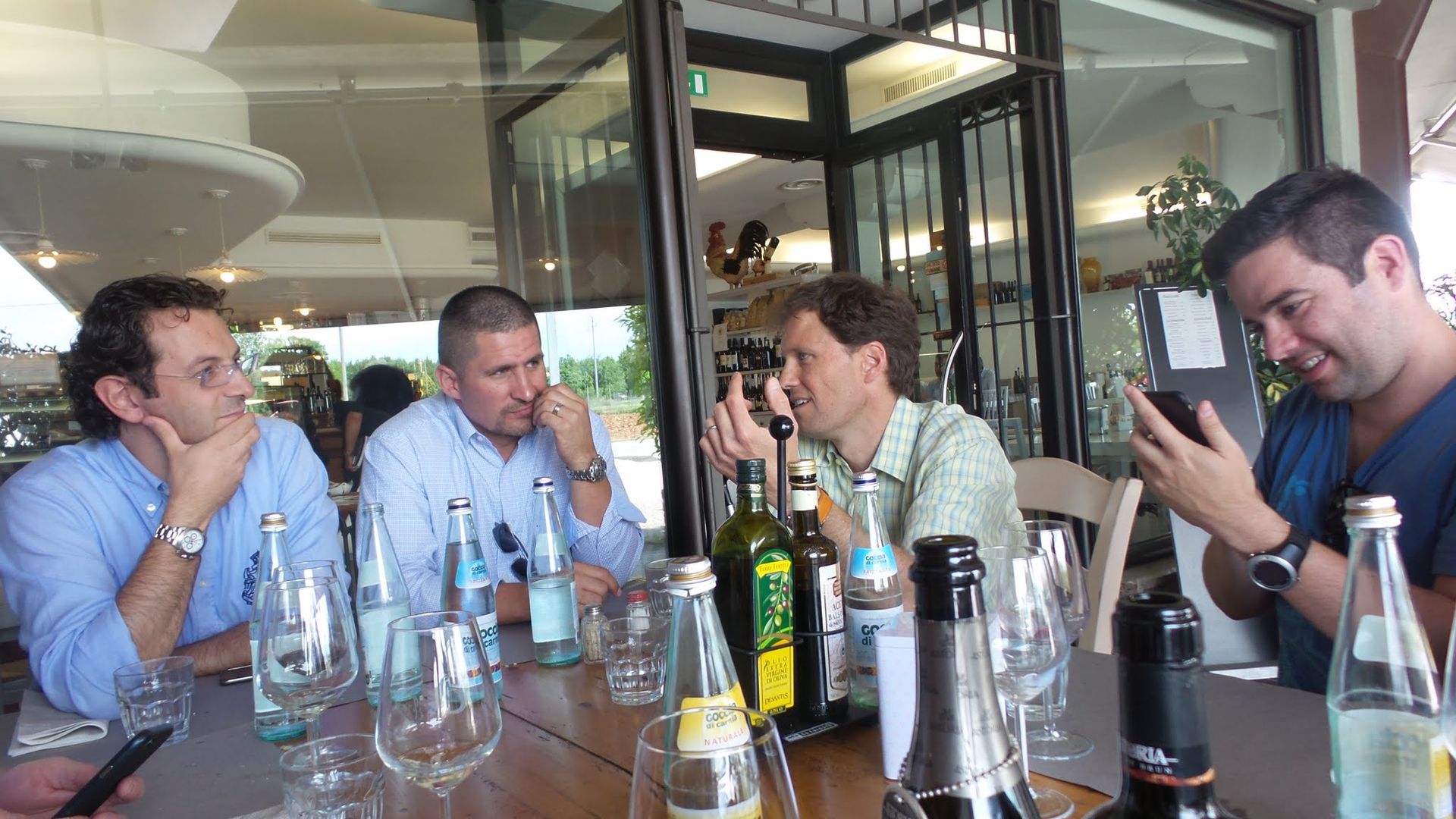 A group of men are sitting at a table with wine bottles and glasses.