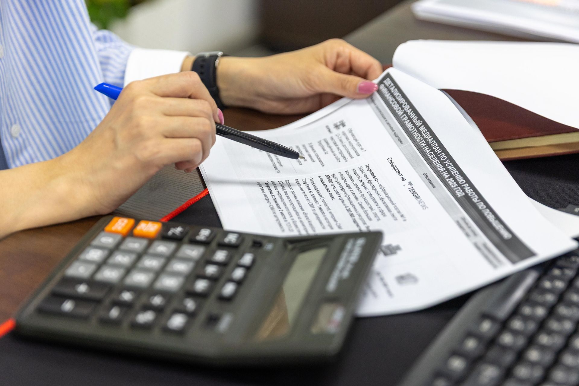 An accountant working with documents and a calculator at a desk in a modern office.