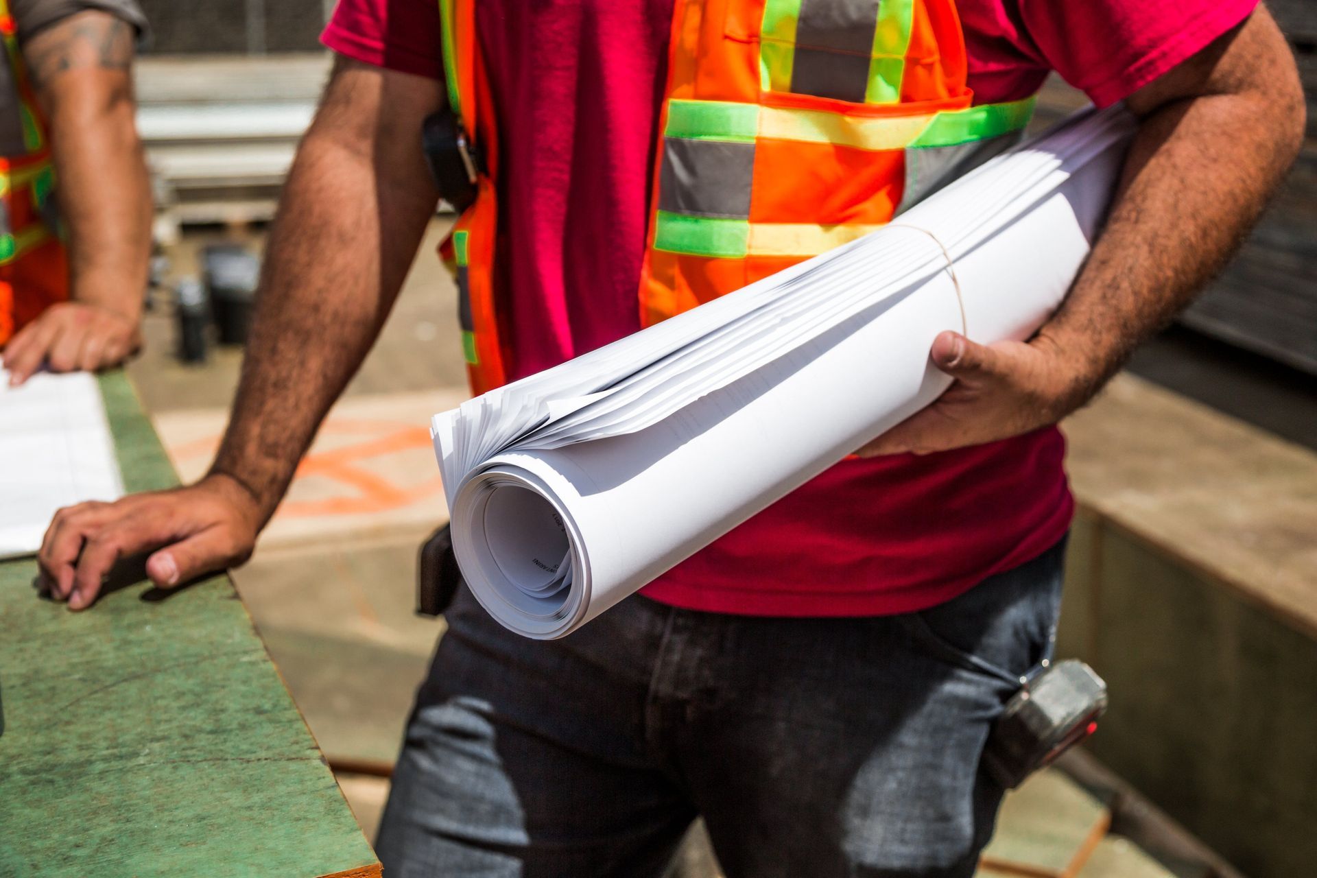 A construction project manager in a hard hat reviewing building plans on a job site.