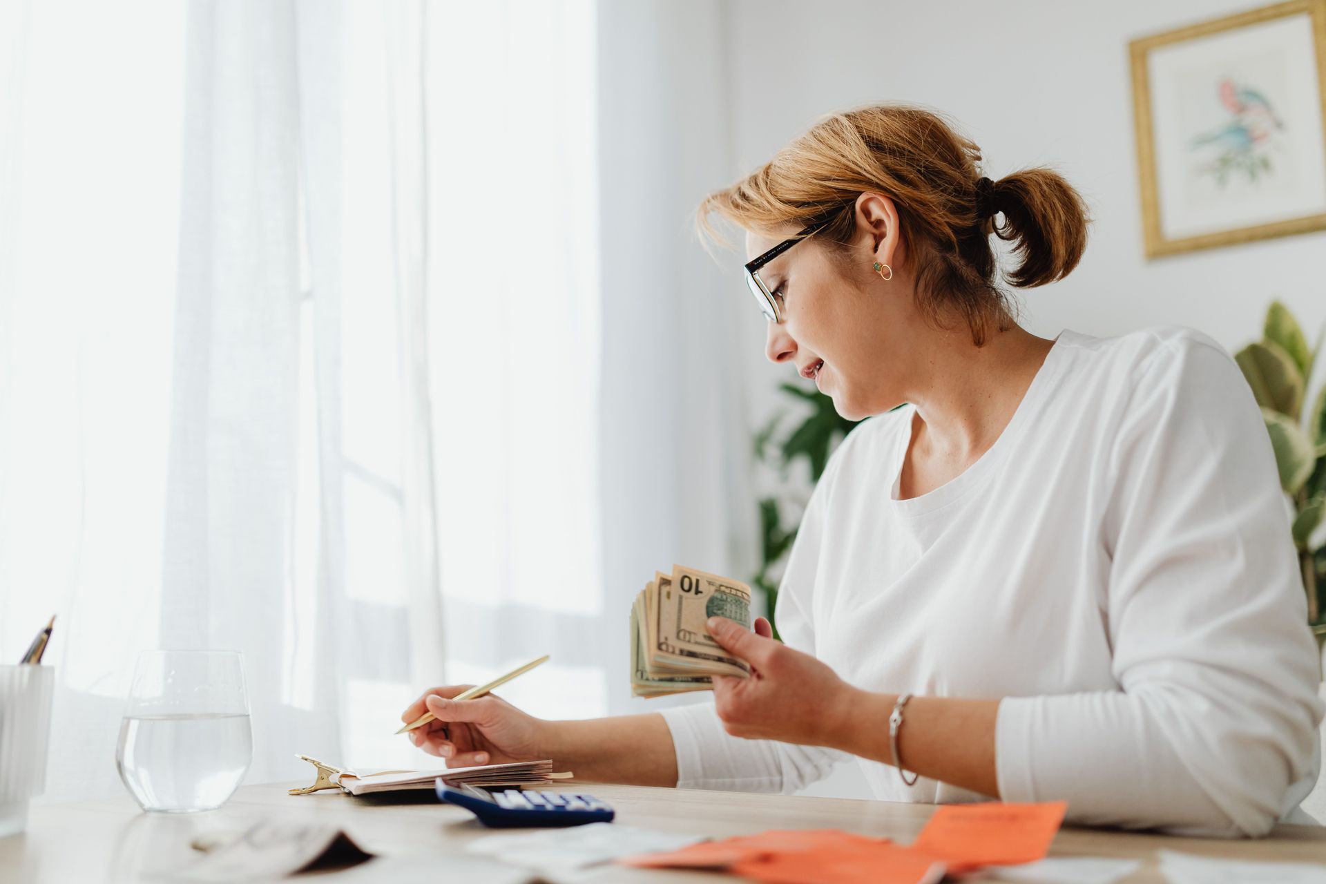 A small business owner reviewing budget paperwork and planning finances at a desk in a bright modern office.