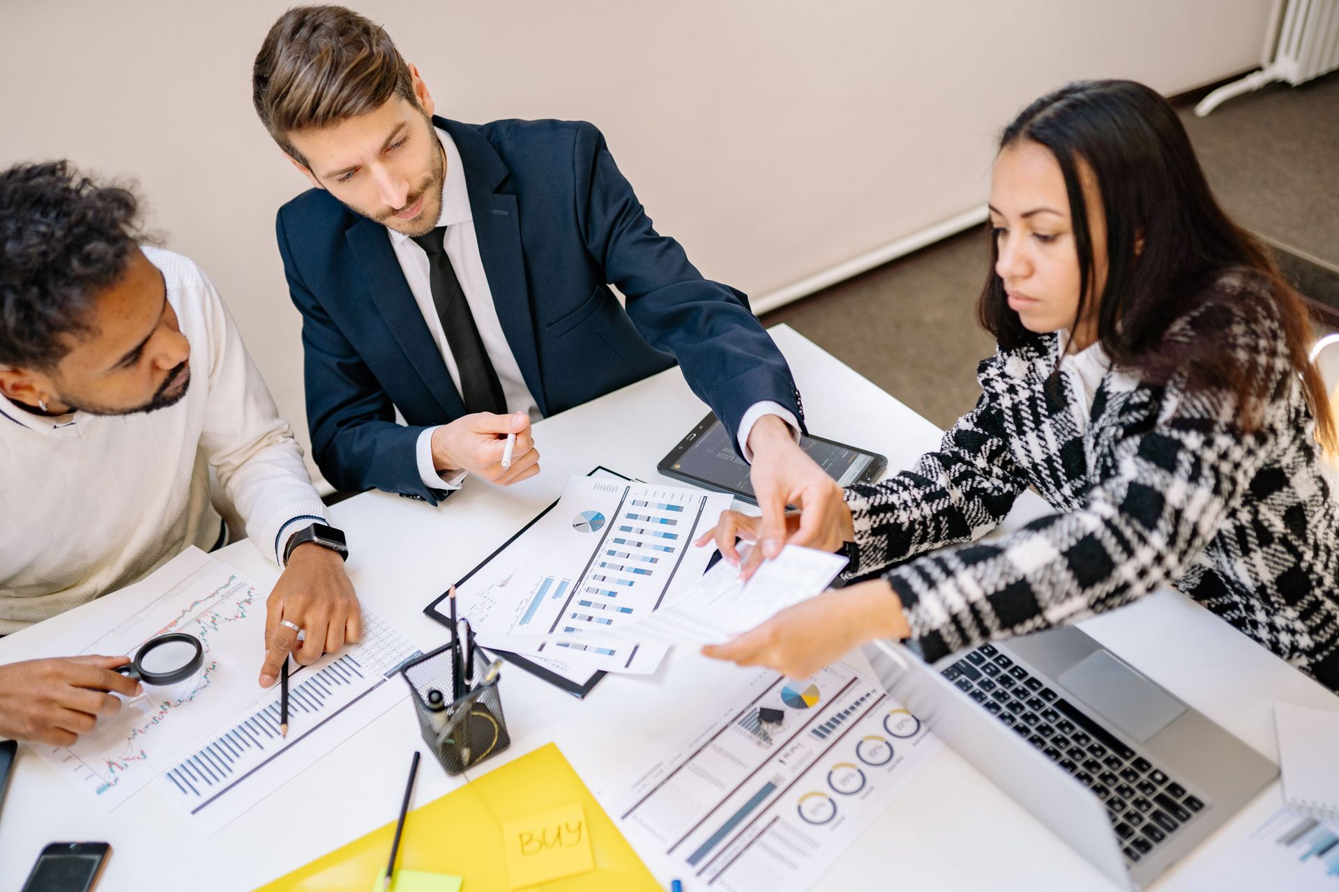 A small business team collaborating around a table in a bright modern office with large windows and natural light.