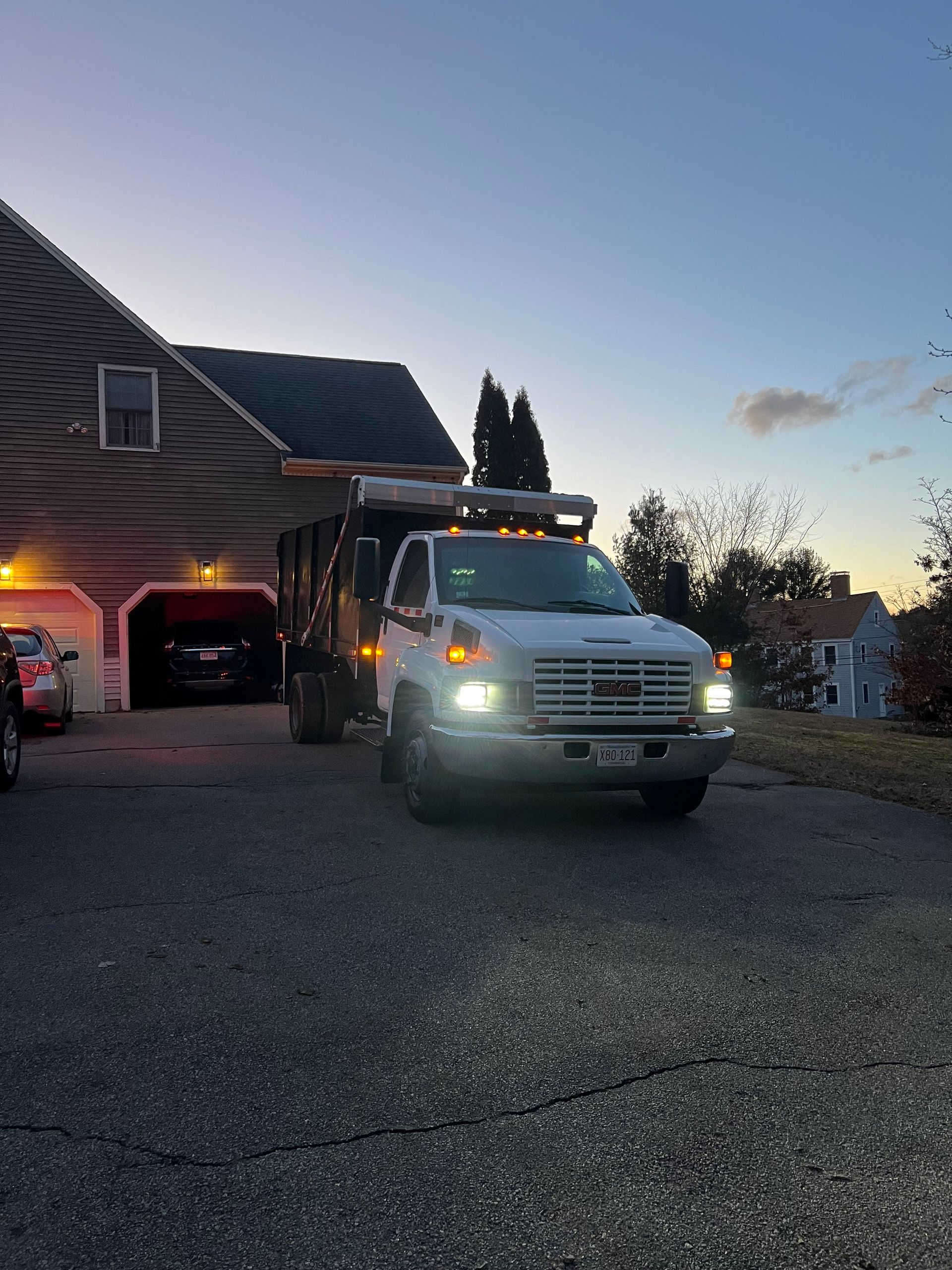 A dump truck is parked in a driveway in front of a house.