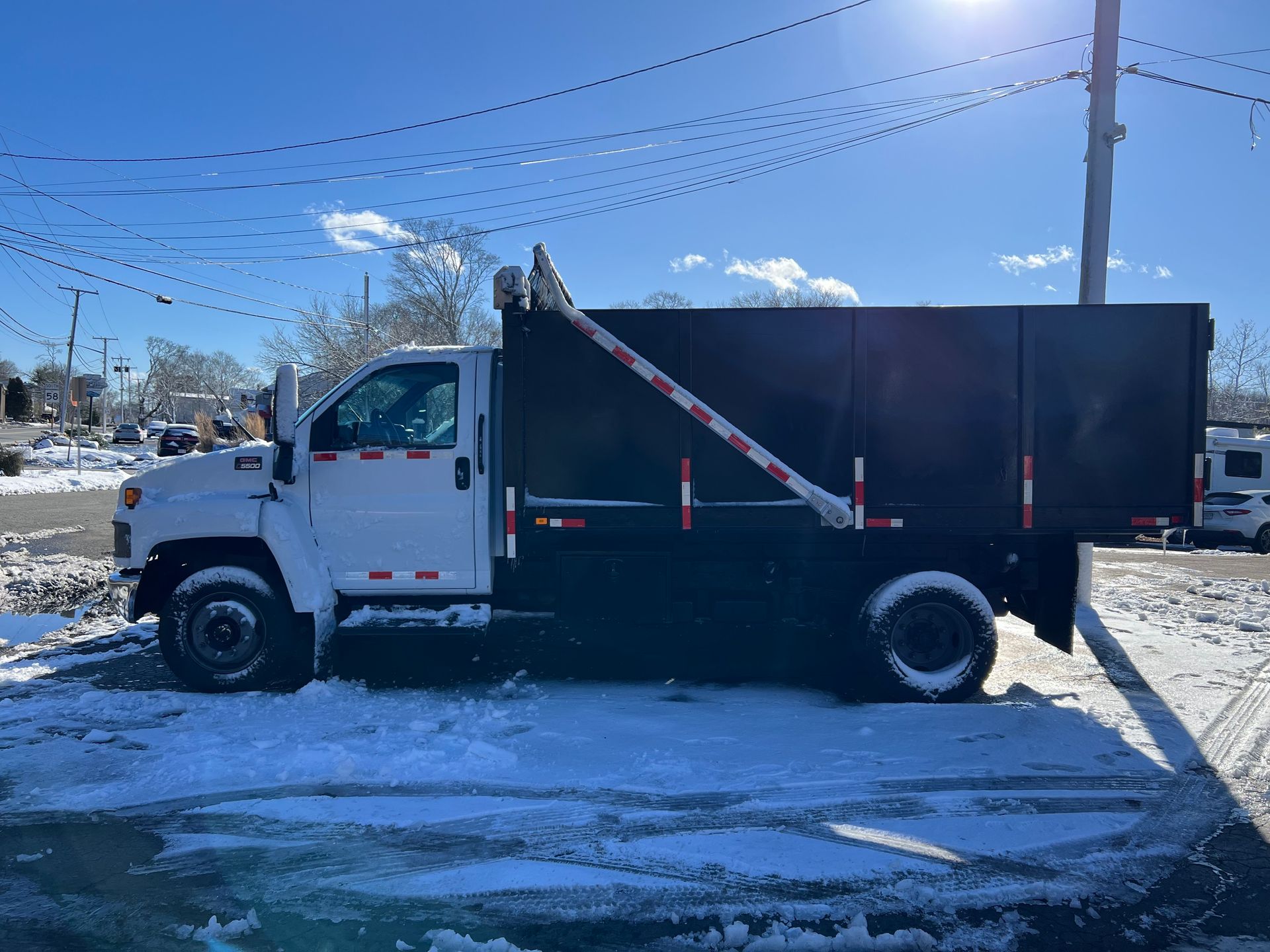 A dump truck is parked in the snow in a parking lot.