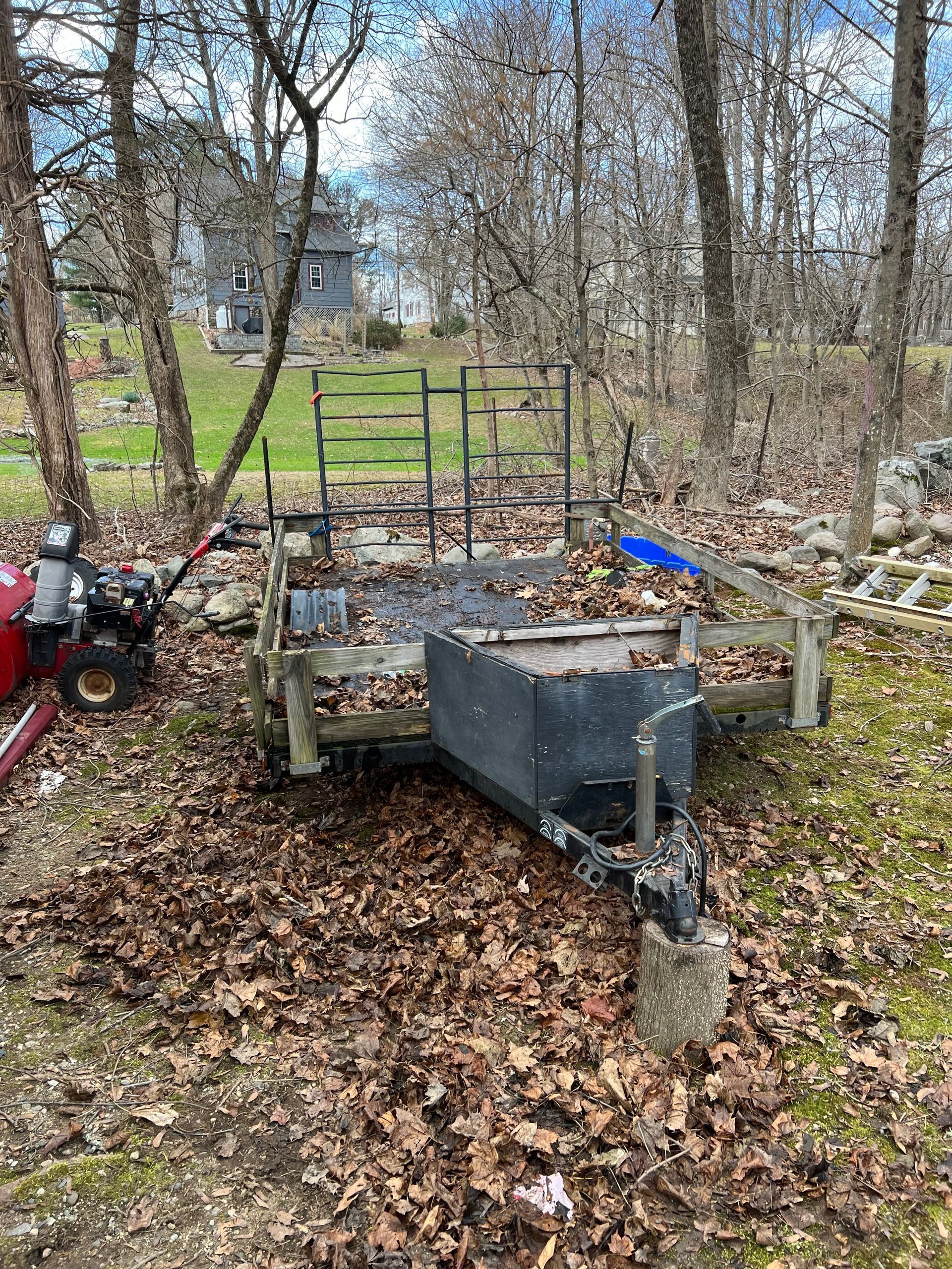 A trailer is sitting on top of a pile of leaves in the middle of a forest.