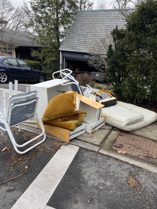 A pile of junk is sitting on the side of the road in front of a house.