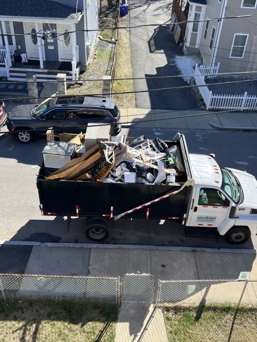 A dump truck filled with junk is parked on the side of the road.