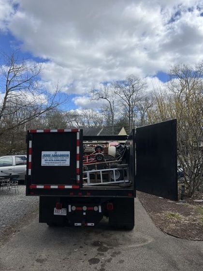 A black truck is parked in a driveway with its doors open.