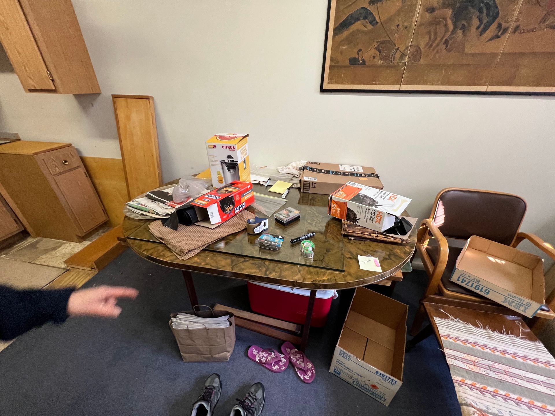 A person is pointing at a messy table in a room.