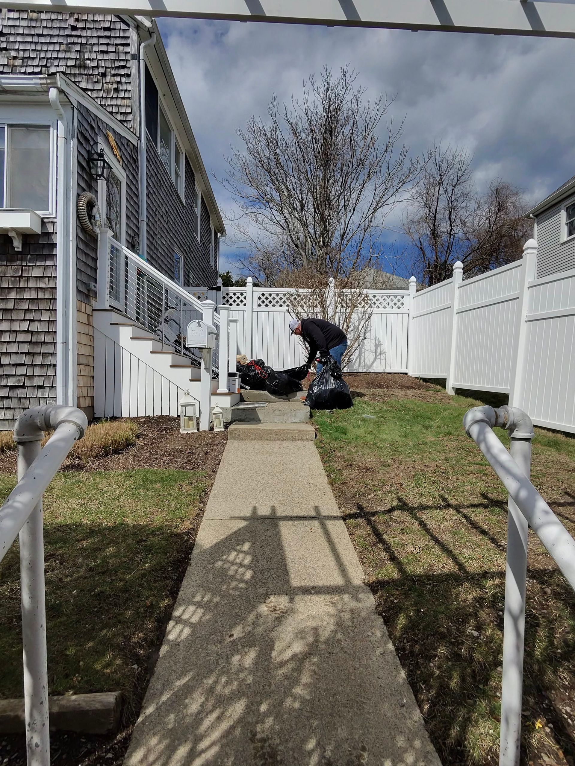 A man is standing on a sidewalk in front of a house.