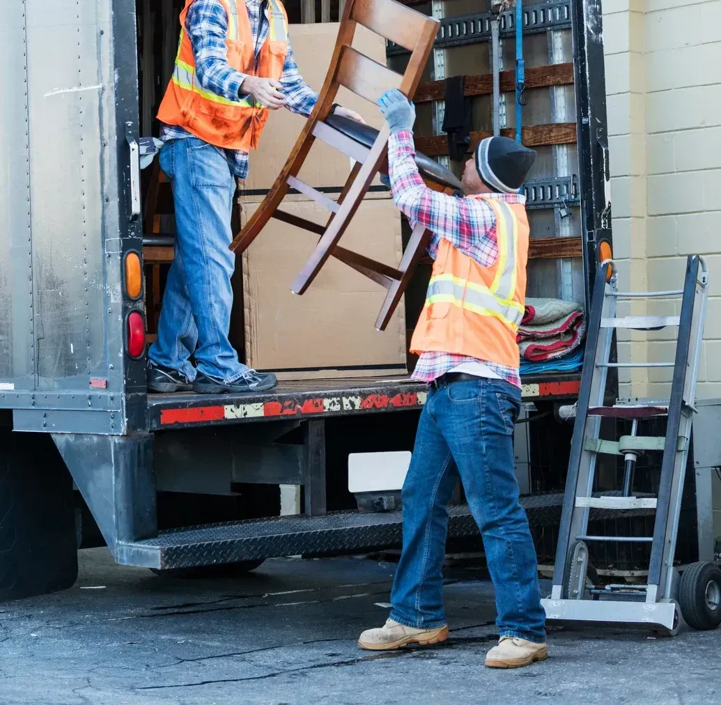 Two men are loading a chair into a truck.