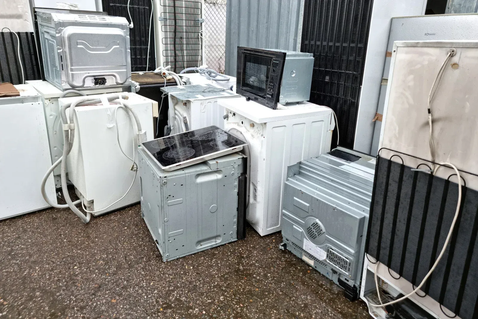 A bunch of old appliances are stacked on top of each other on the ground.