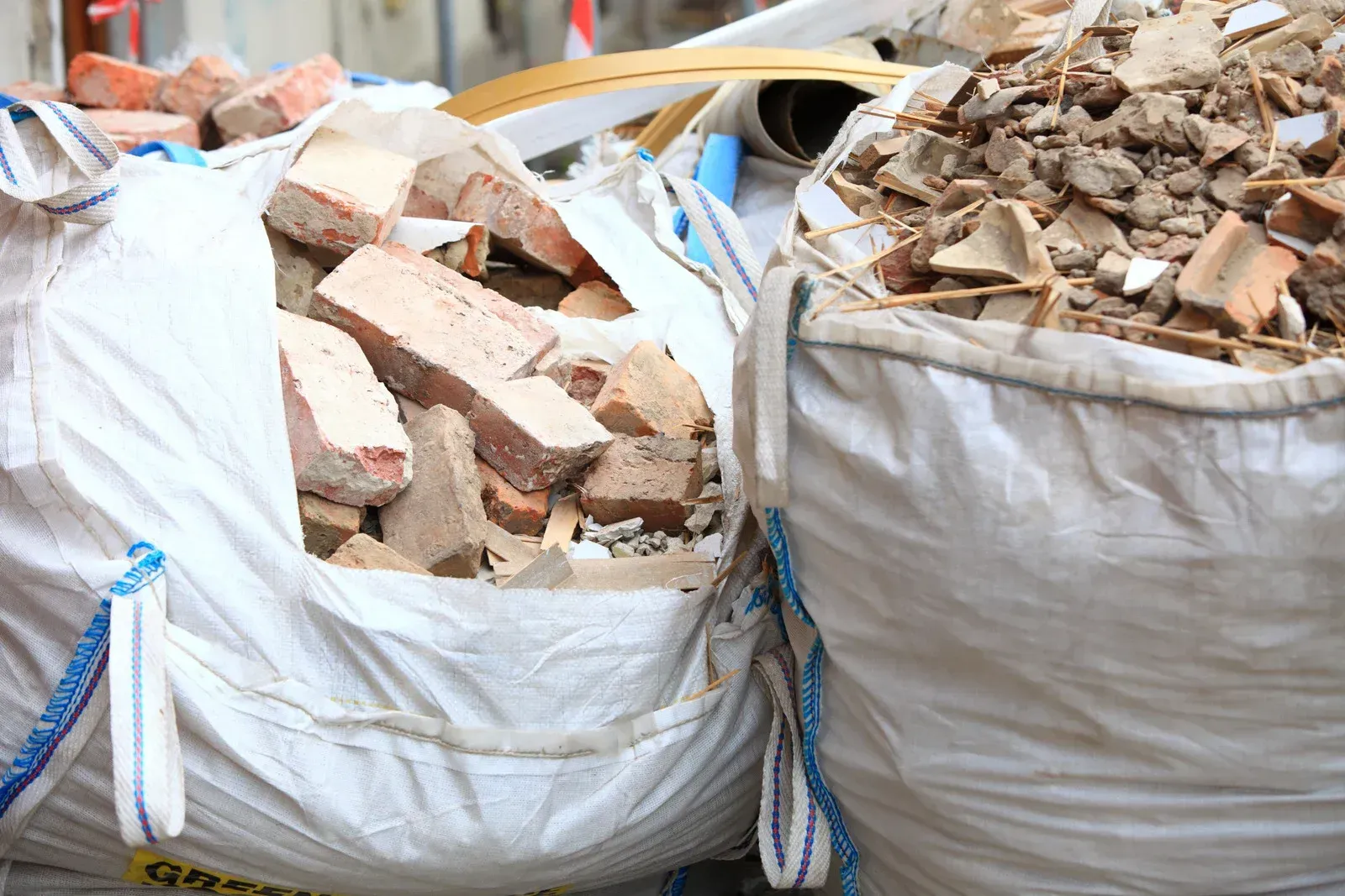 Two bags filled with bricks and rocks are sitting next to each other.