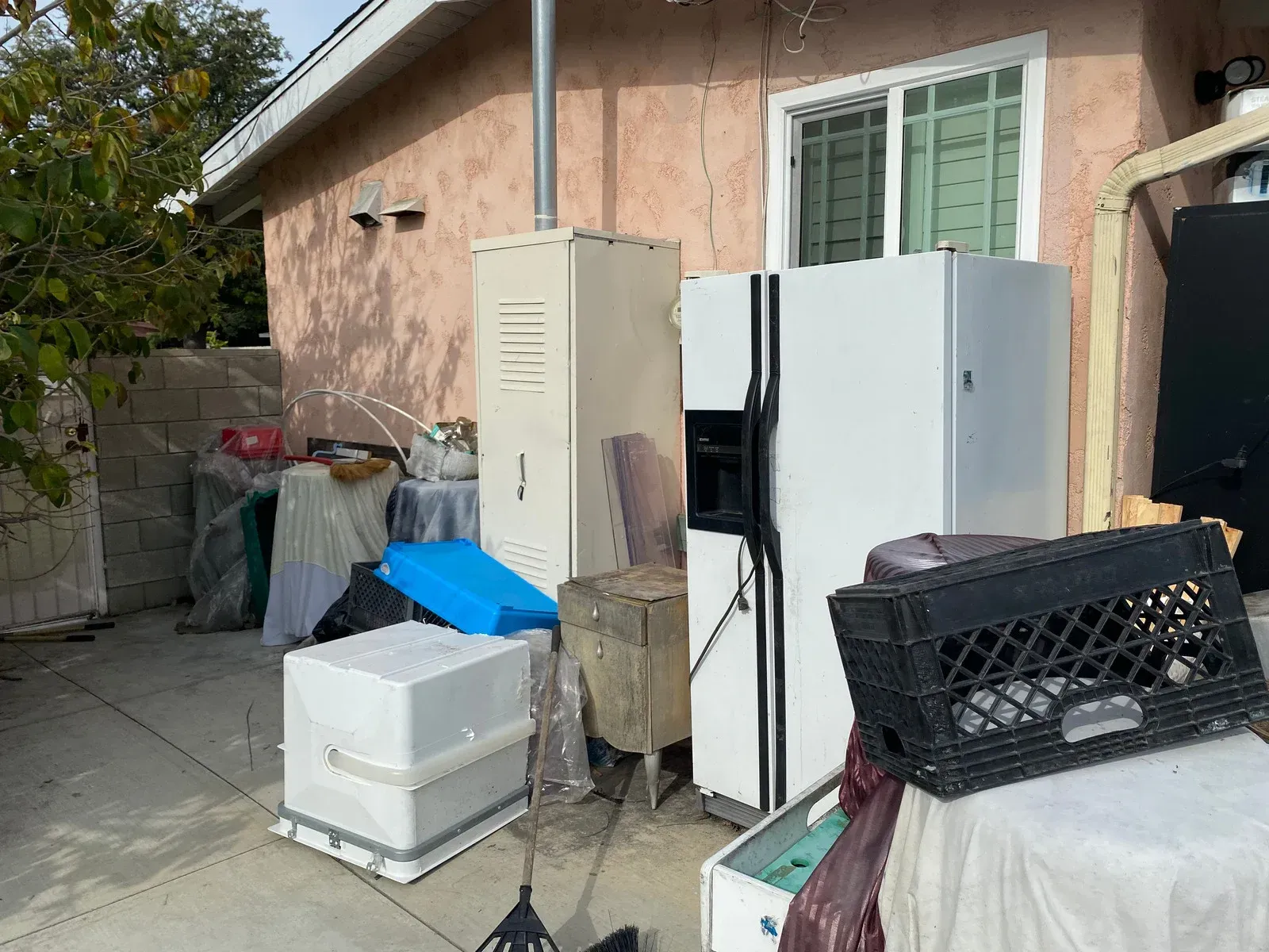 A house with a lot of junk in front of it , including a refrigerator.