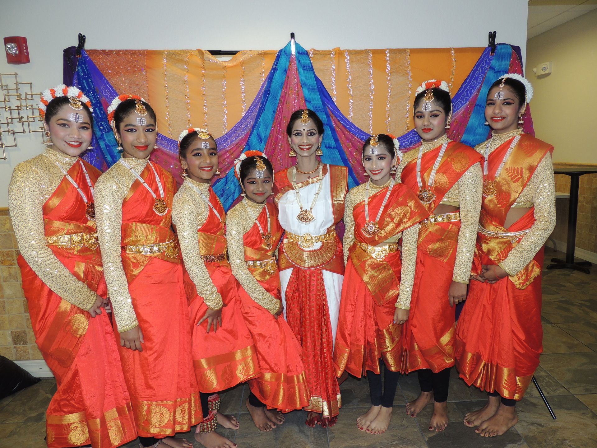 Group of women in colorful traditional Indian dance attire, posing indoors.