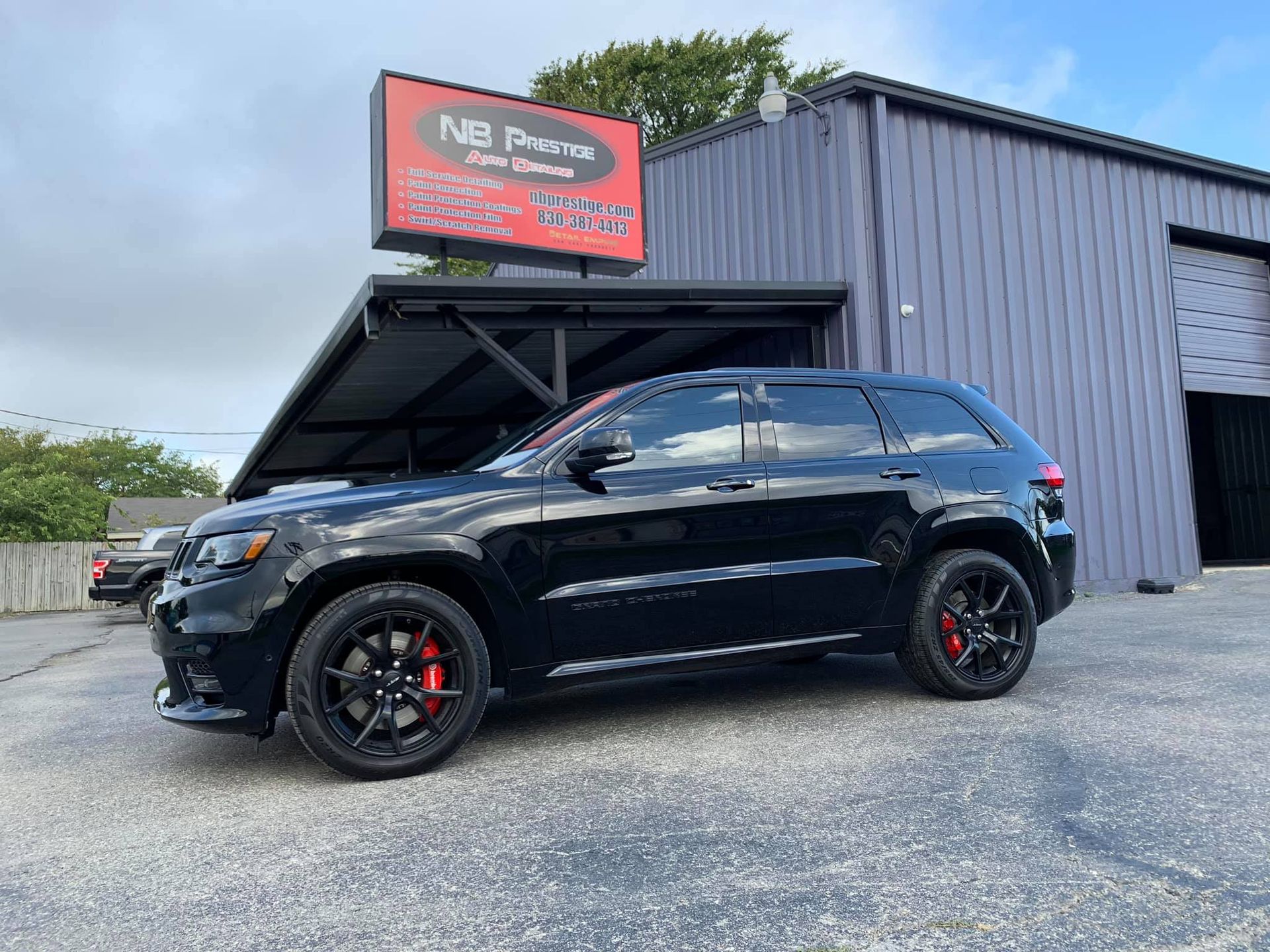 A black jeep grand cherokee is parked in front of a building.