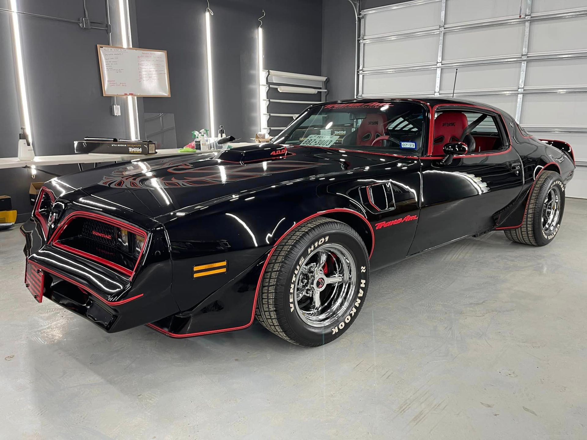 A black car with red trim is parked in a garage.