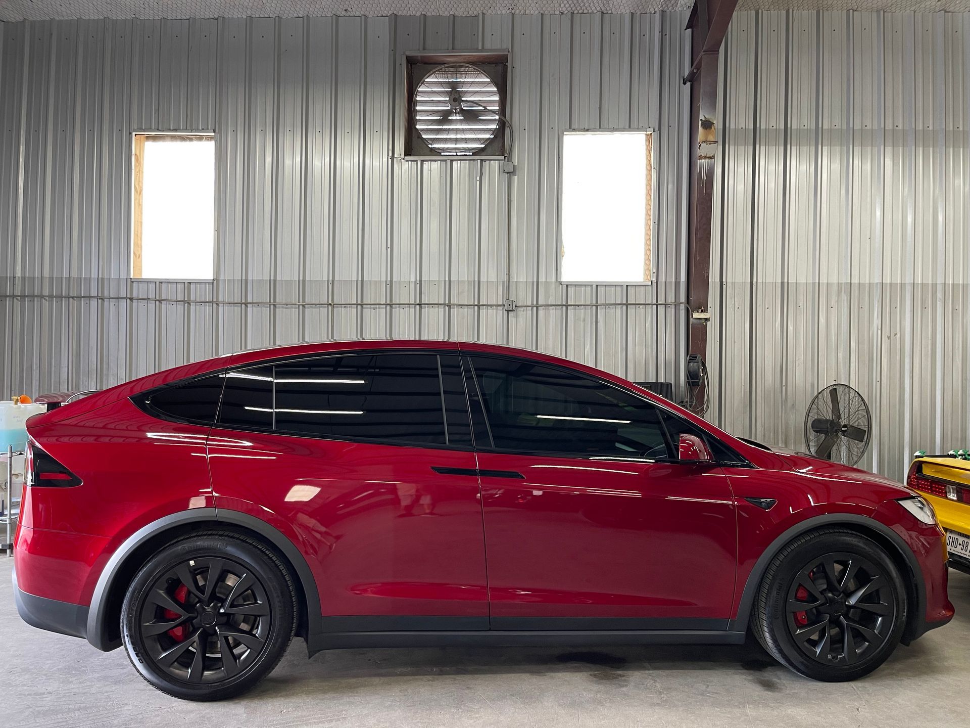 A red tesla model x is parked in a garage.