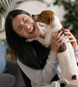 A woman is holding a brown and white dog in her arms.