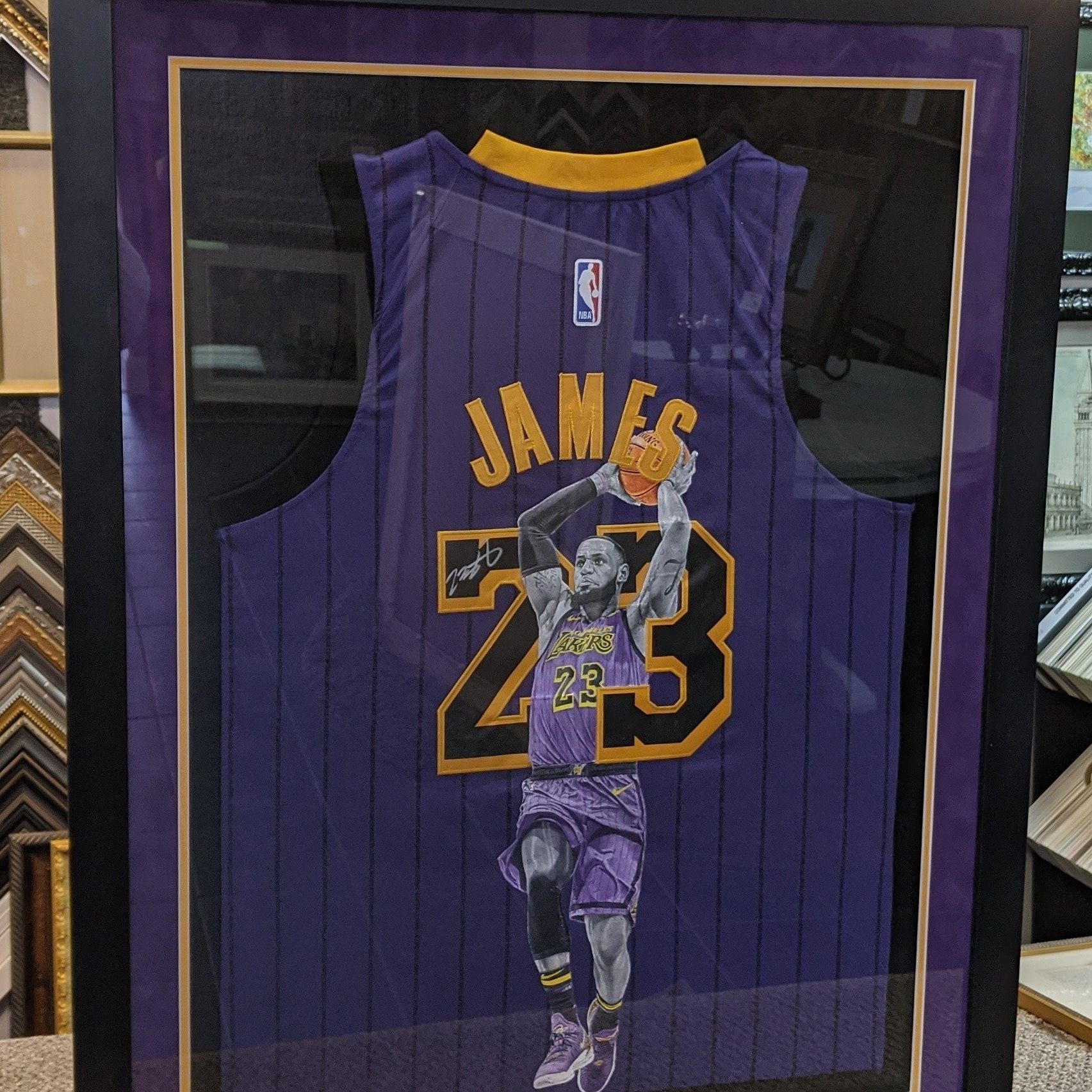 A framed, purple Los Angeles Lakers basketball jersey with a graphic of LeBron James holding a ball, labeled 
