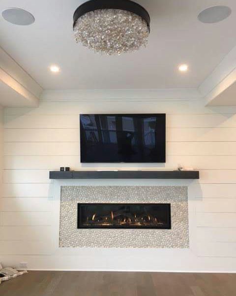 A living room with a fireplace and a flat screen tv on the wall.