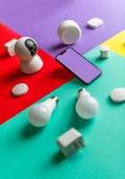 A colorful table with a cell phone , light bulbs , and a camera.