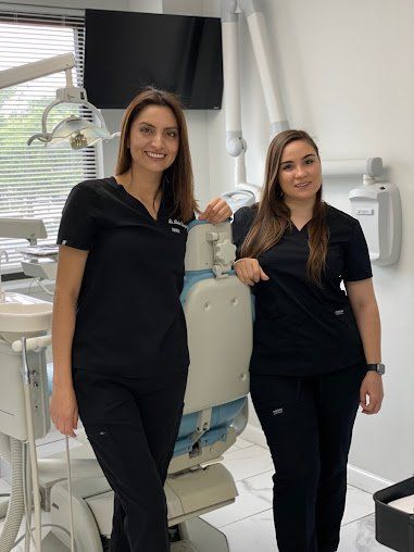 Two female dentists are standing next to each other in a dental office.