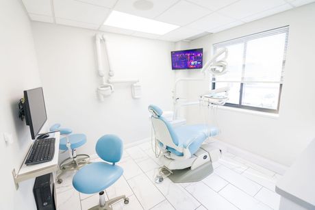 A dental office with a dental chair and a computer.