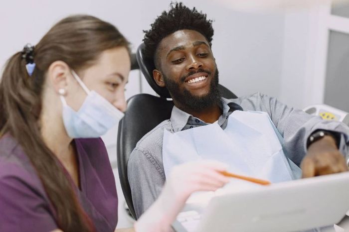 A man is sitting in a dental chair looking at a tablet.