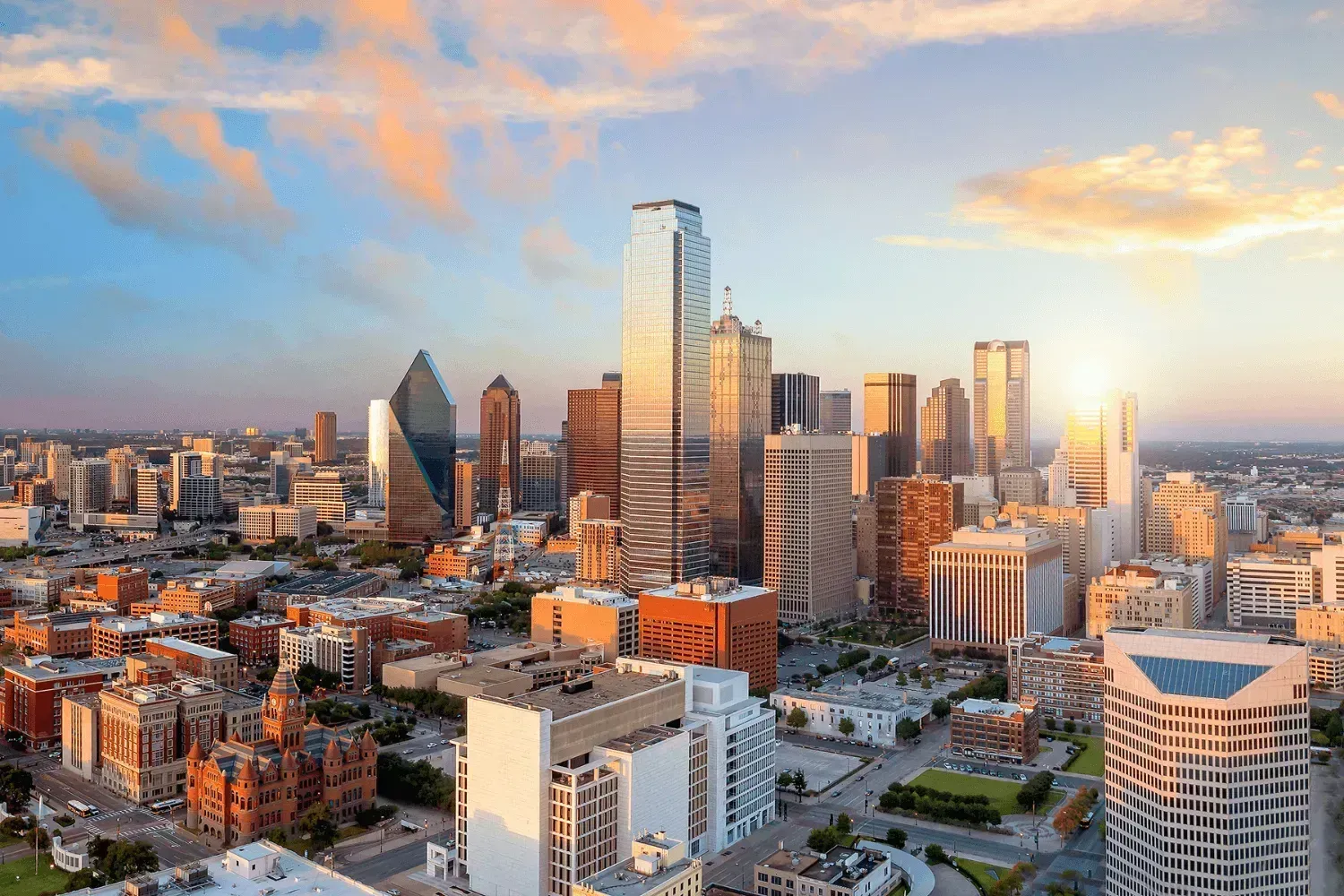 Sunset city skyline with tall glass skyscrapers and warm orange-lit buildings
