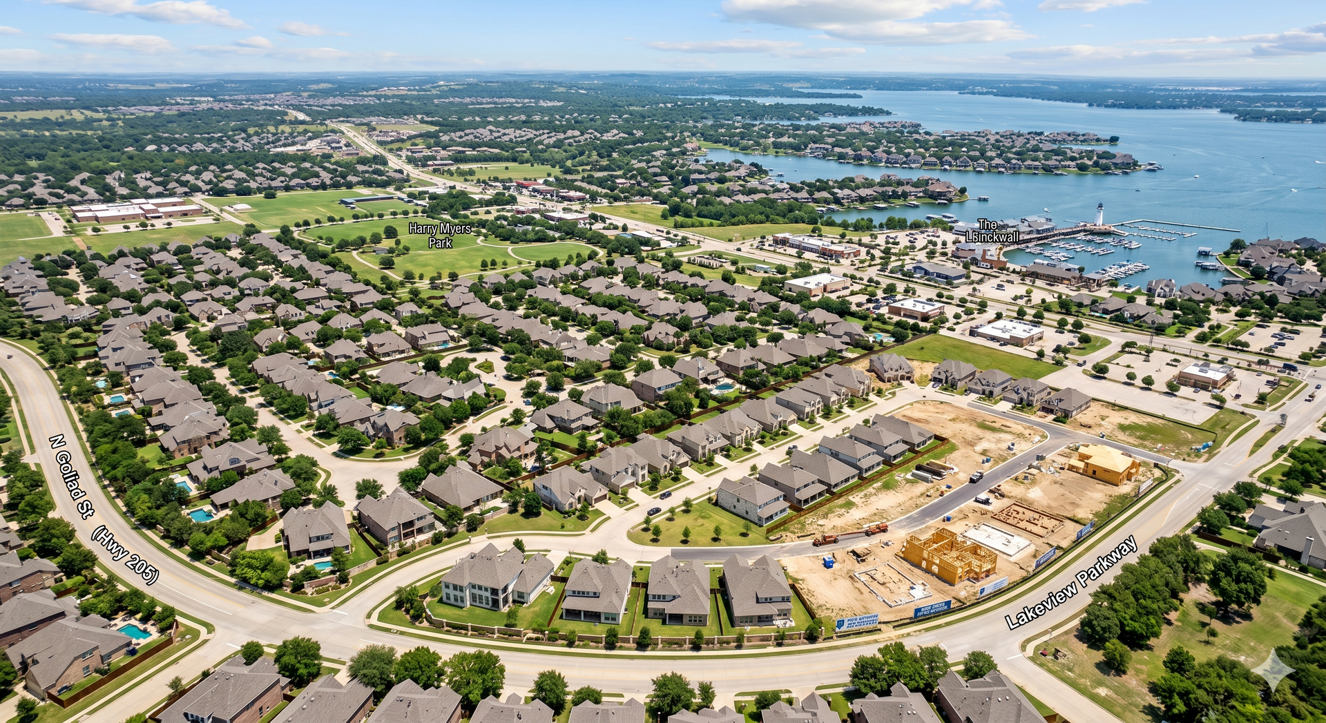 Aerial view of a suburban neighborhood beside a blue bay and marina on a sunny day