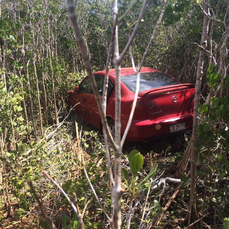 Red car crashed off road, surrounded by dense vegetation — Banjo's Anytime Towing in Humpty Doo, NT