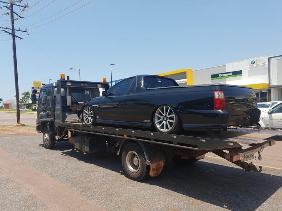 Black ute on a tow truck, roadside. Sunny day, commercial area — Banjo's Anytime Towing in Humpty Doo, NT