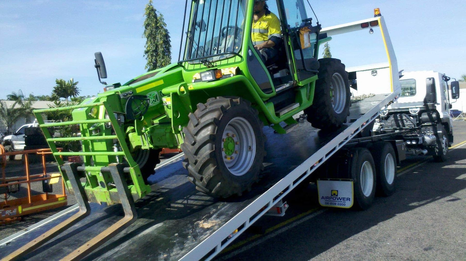 Green Construction Vehicle on a Tow Truck, Preparing to Be Transported — Banjo's Anytime Towing in Winnellie, NT