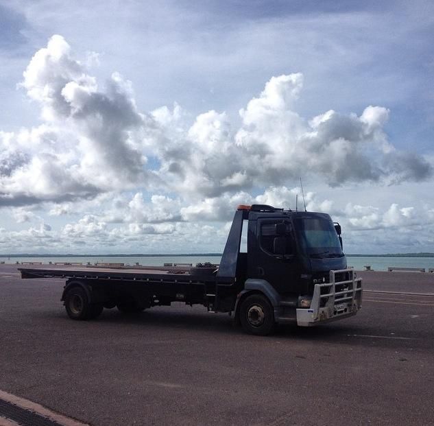 Black Flatbed Tow Truck Parked on Pavement With Cloudy Sky — Banjo's Anytime Towing in Casuarina, NT