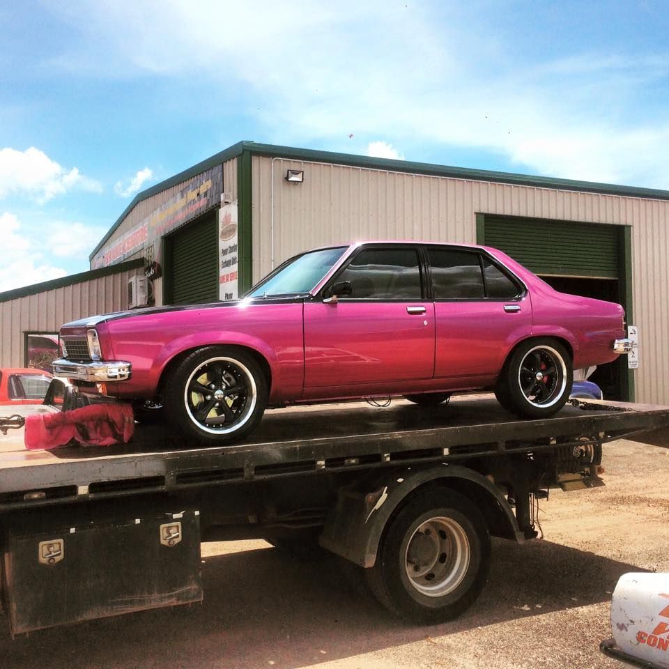 Pink Car on a Flatbed Tow Truck in Front of a Garage — Banjo's Anytime Towing in Howard Springs, NT