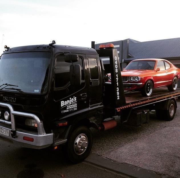 Black Tow Truck With a Vintage Orange Car on Its Bed — Banjo's Anytime Towing in Darwin, NT