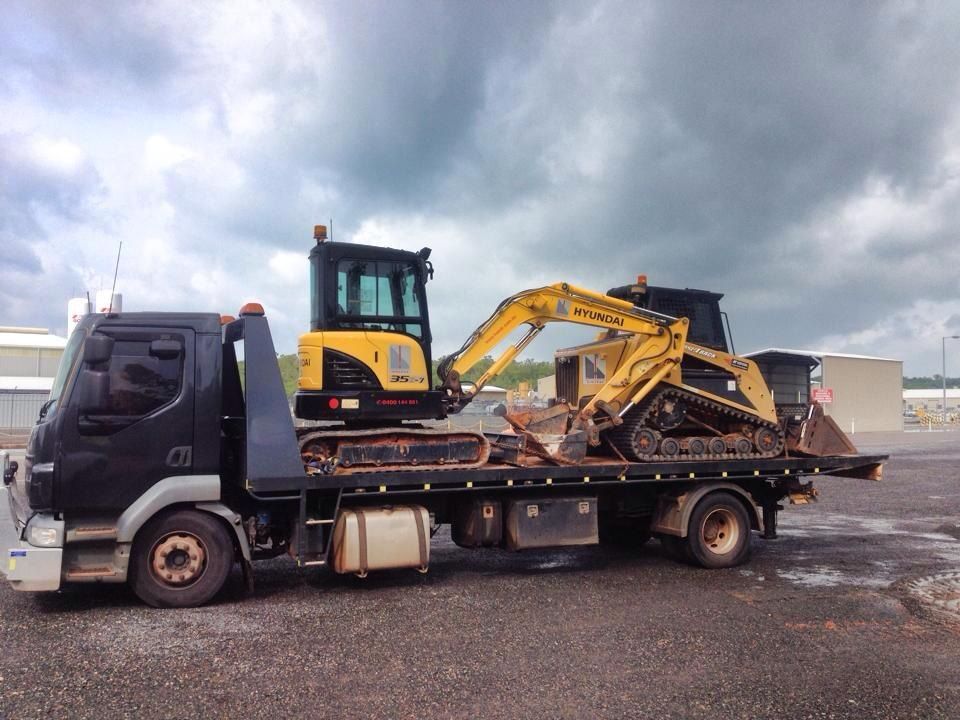 A Flatbed Truck Carrying a Yellow Excavator and a Black Skid Steer 
— Banjo's Anytime Towing in Humpty Doo, NT