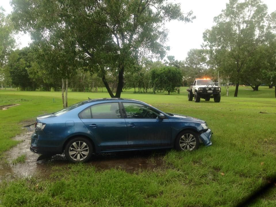 Blue Car Damaged in a Grassy Field, With a Tow Truck in the Background 
— Banjo's Anytime Towing in Humpty Doo, NT