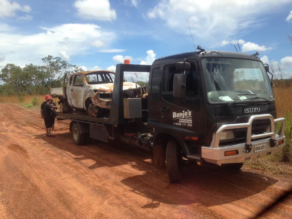 Tow Truck on a Dirt Road With a Severely Damaged White Pickup Truck — Banjo's Anytime Towing in Humpty Doo, NT