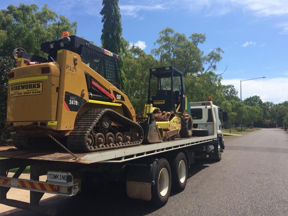 Flatbed truck with two construction vehicles on a road under a sunny sky — Banjo's Anytime Towing in Humpty Doo, NT