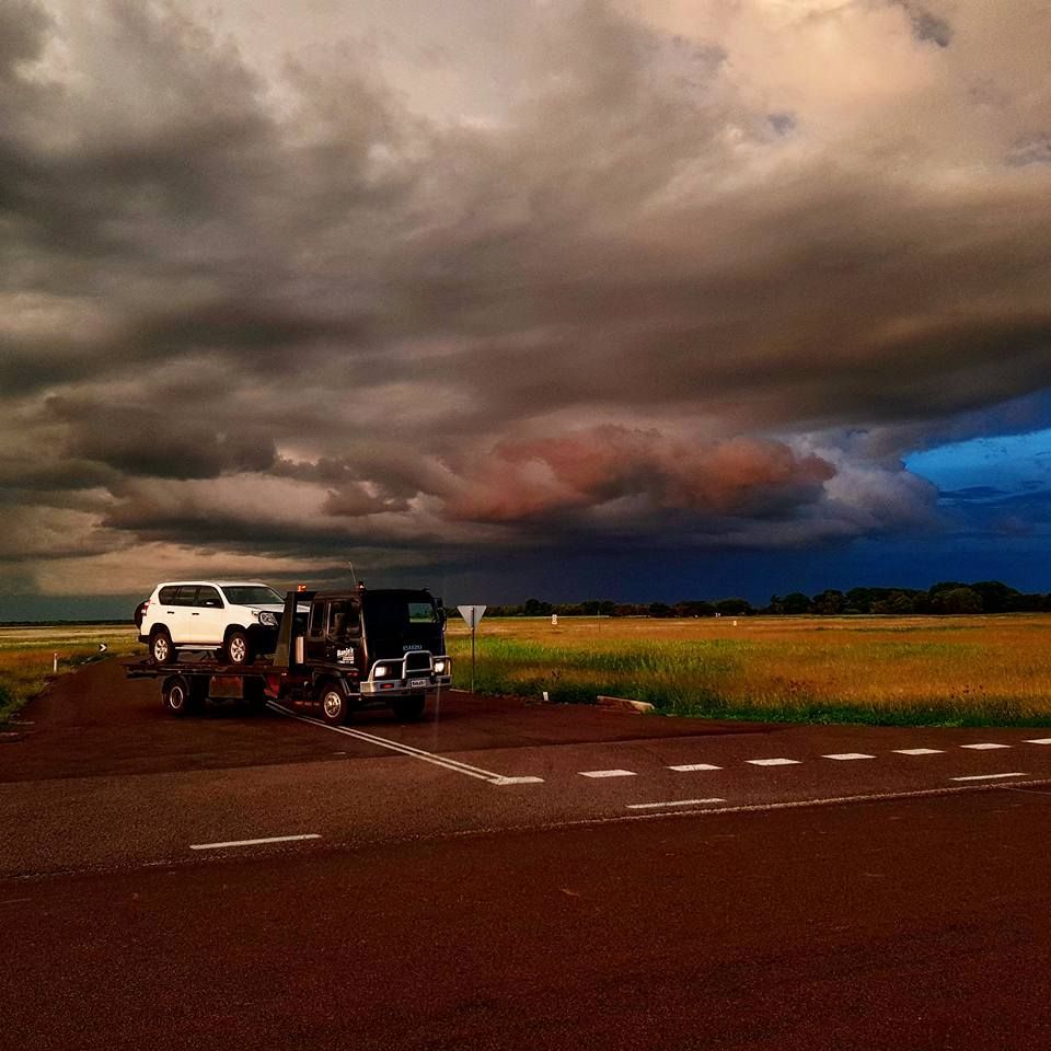 Tow Truck on a Dirt Road With a Severely Damaged White Pickup Truck — Banjo's Anytime Towing in Humpty Doo, NT