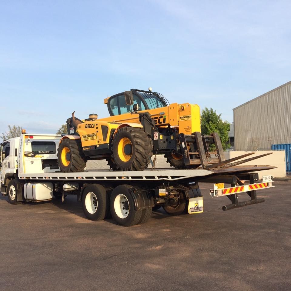 Flatbed Truck Transporting a Yellow Construction Forklift Outdoors — Banjo's Anytime Towing in Humpty Doo, NT