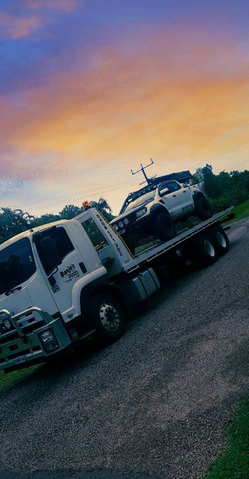 Tow truck hauling a white car on a gravel road at sunset — Banjo's Anytime Towing in Humpty Doo, NT
