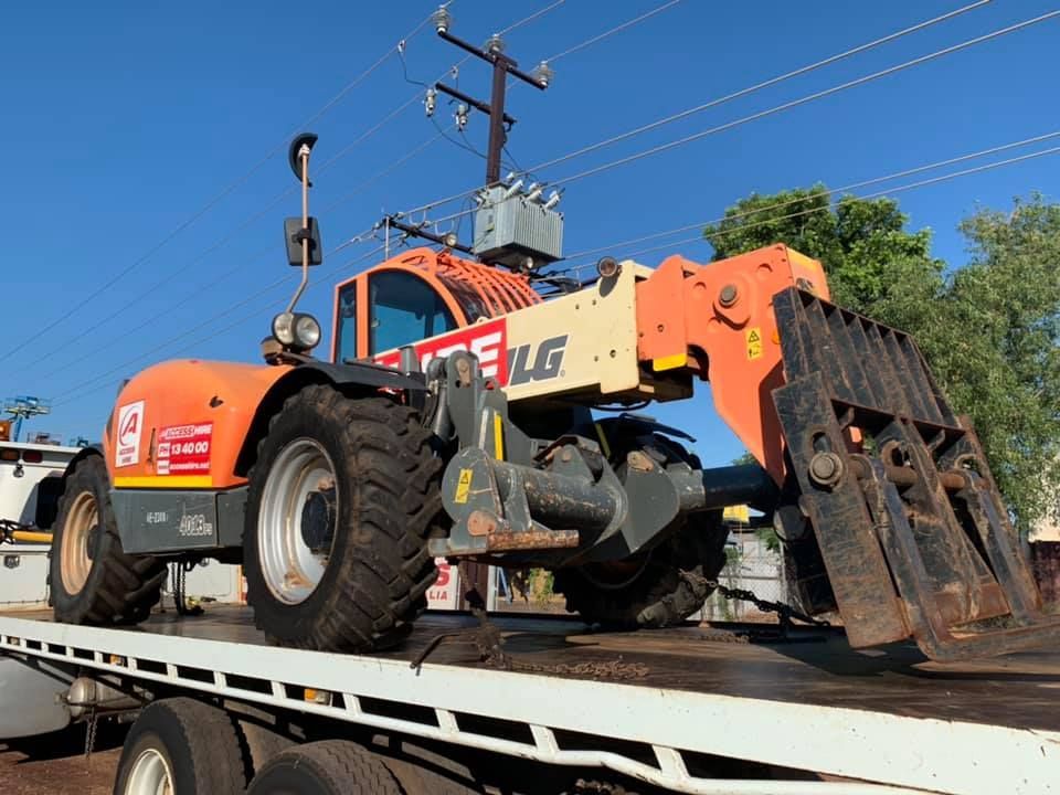 Orange JLG telehandler on a flatbed truck, near power lines. Sunny day — Banjo's Anytime Towing in Humpty Doo, NT