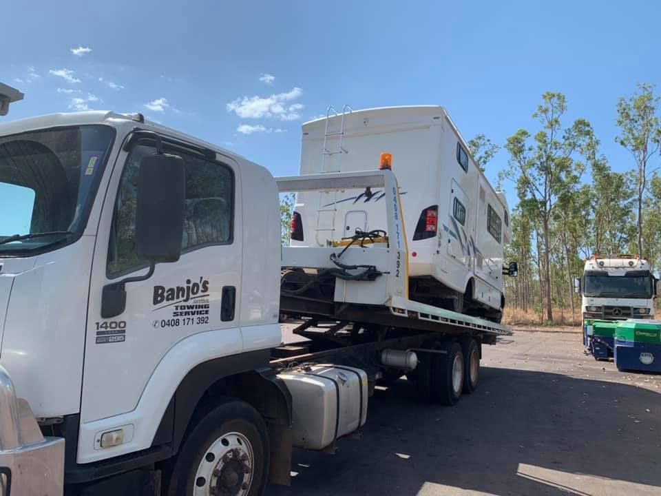 A white tow truck carrying a white RV on a sunny day — Banjo's Anytime Towing in Humpty Doo, NT