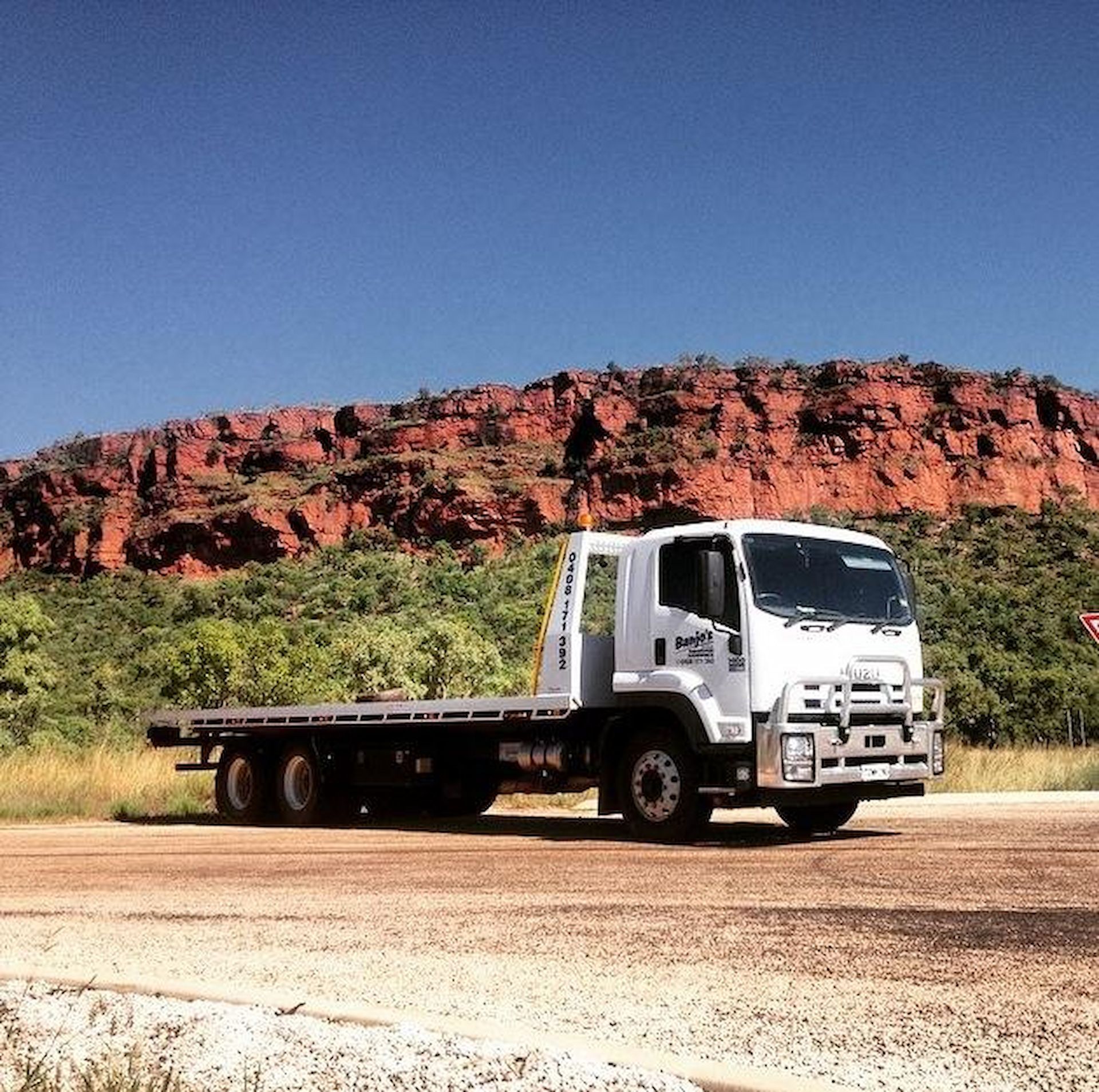 White Flatbed Truck Parked on Dirt Road — Banjo's Anytime Towing in Humpty Doo, NT