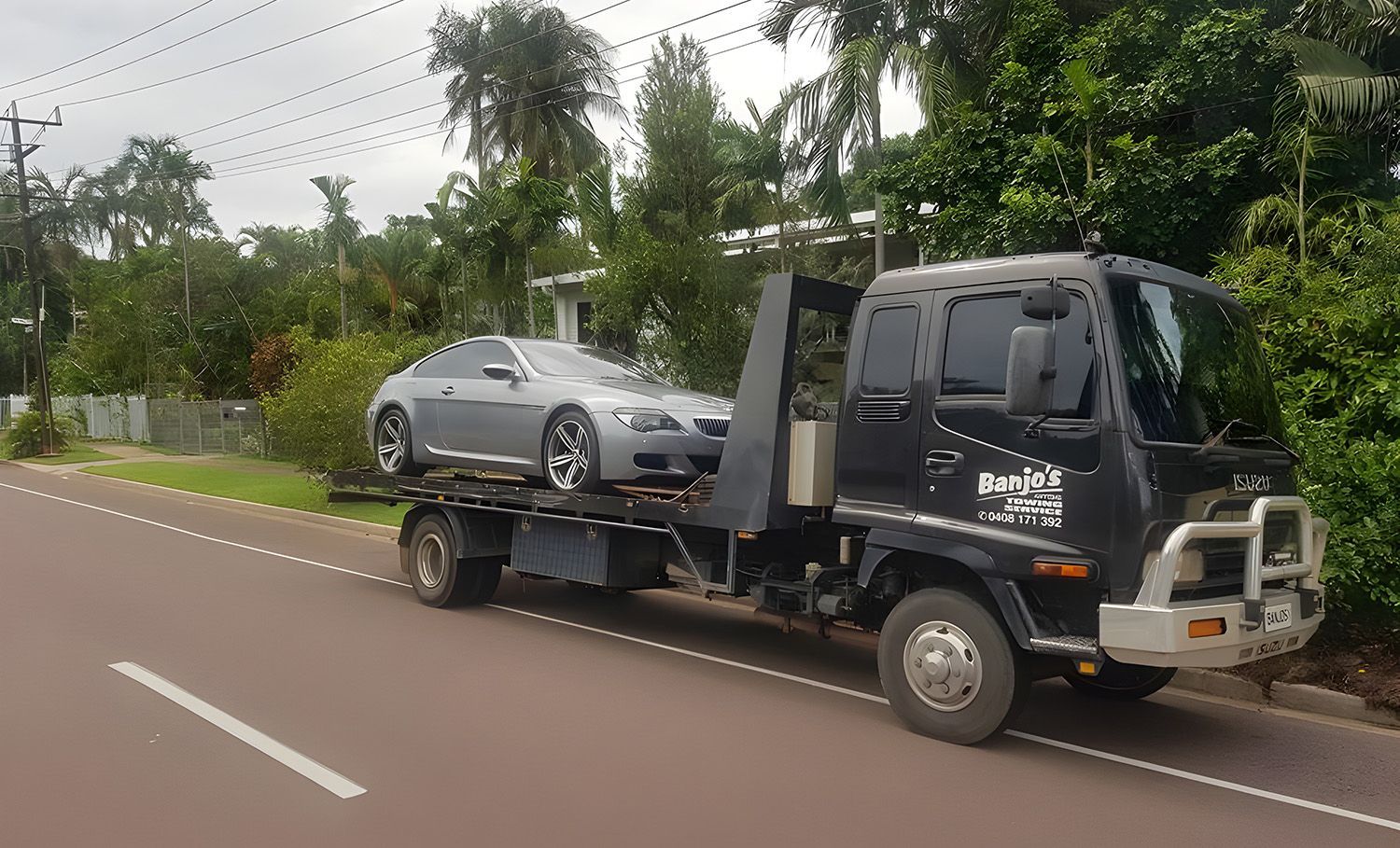 A Silver BMW Coupe Being Transported On The Flatbed Of A Black Tow Truck