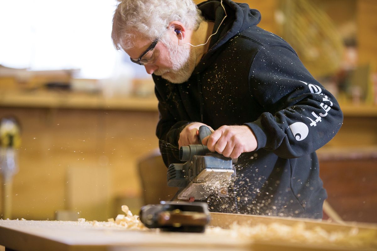 A carpenter cutting wood with a circular saw in our Carhartt Sleee Logo Hoodies